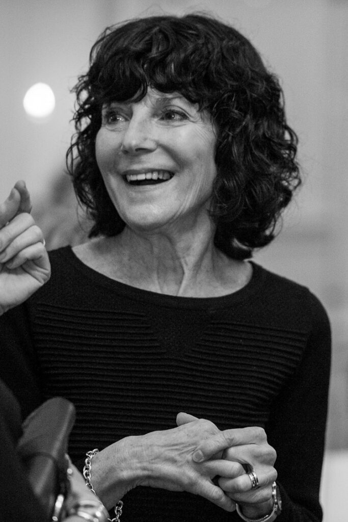 A black and white photo of an older woman laughing.